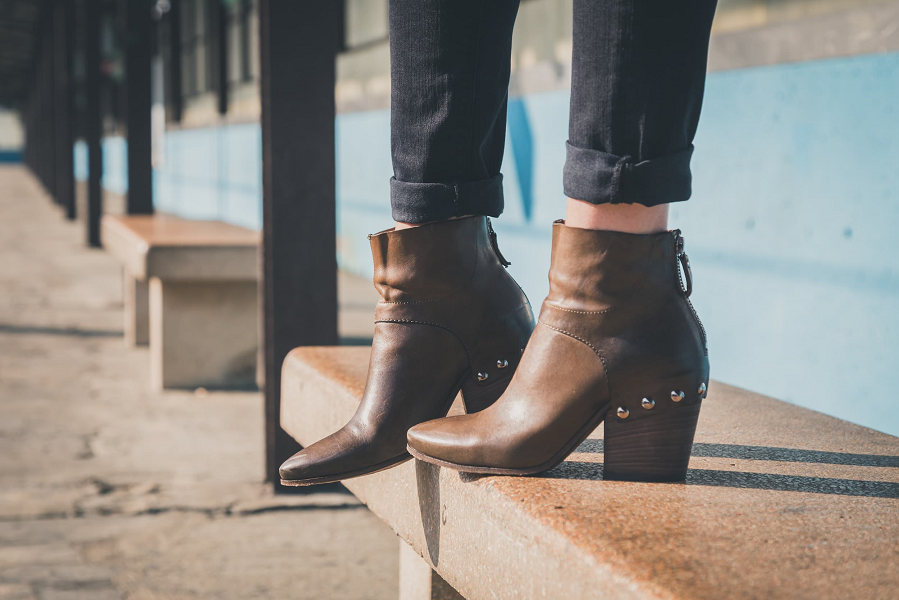 A close-up of a woman wearing brown leather ankle boots with cropped trousers.